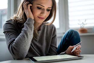 Young woman holding check card looking at her balance online.