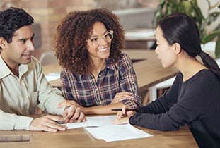 Young couple sitting with banker filling out forms.