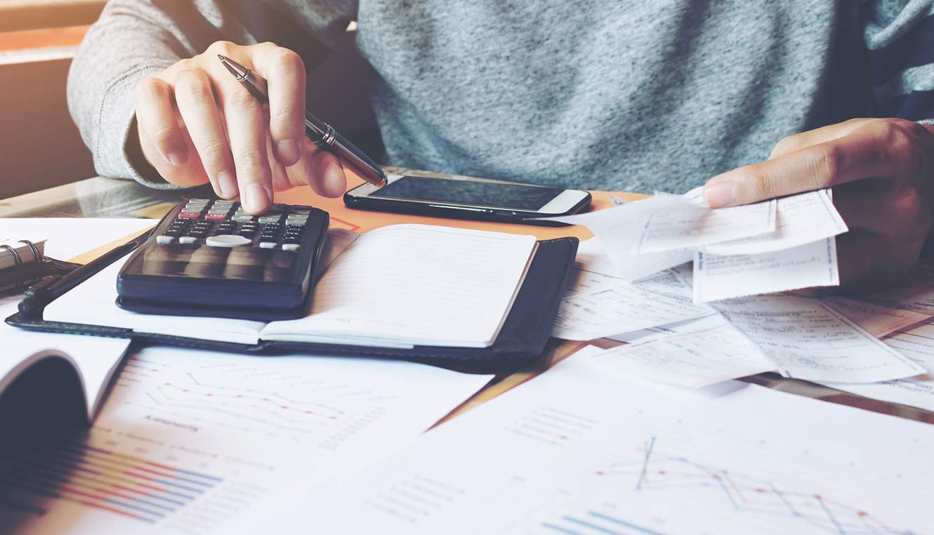 Person using calculator to add up receipts for book keeping.