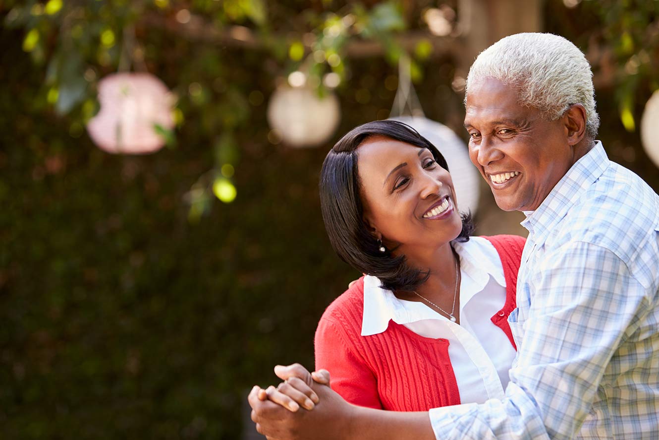 Retired couple dancing and looking happy.