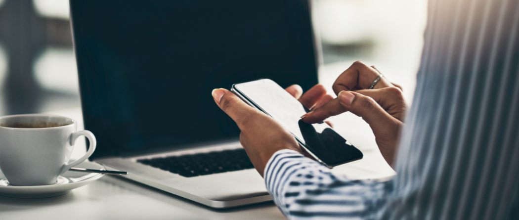 person using cellphone in front of laptop